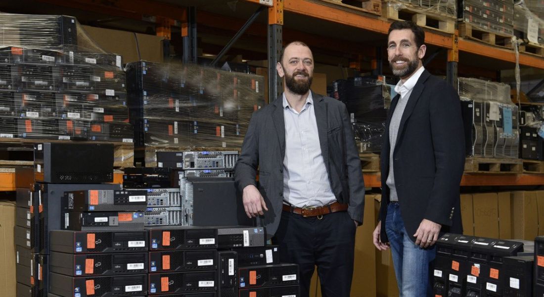 Two bearded men in sports jackets standing in a room full of IT equipment.