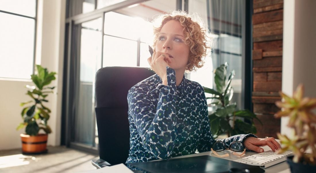 View of woman with blonde curly hair staring off to the distance lost in thought.