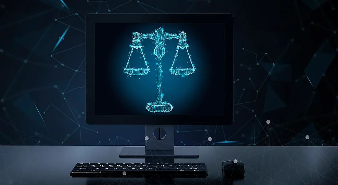 Illustration of a computer screen on a desktop displaying a digitised image of the scales of justice.