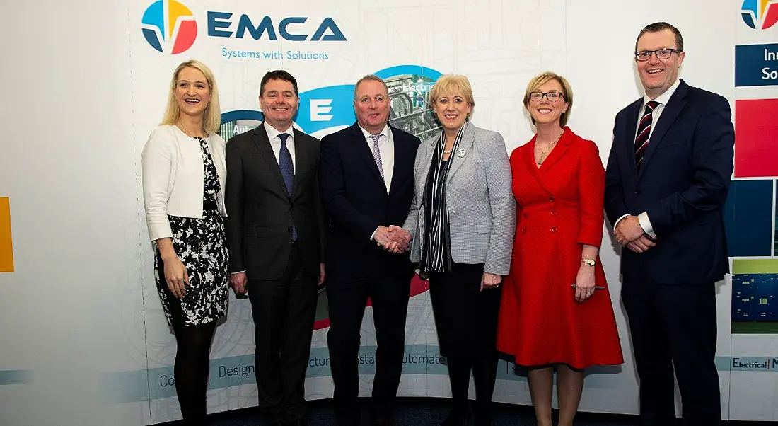 Three men and three women stand side by side in front of an EMCA sign.