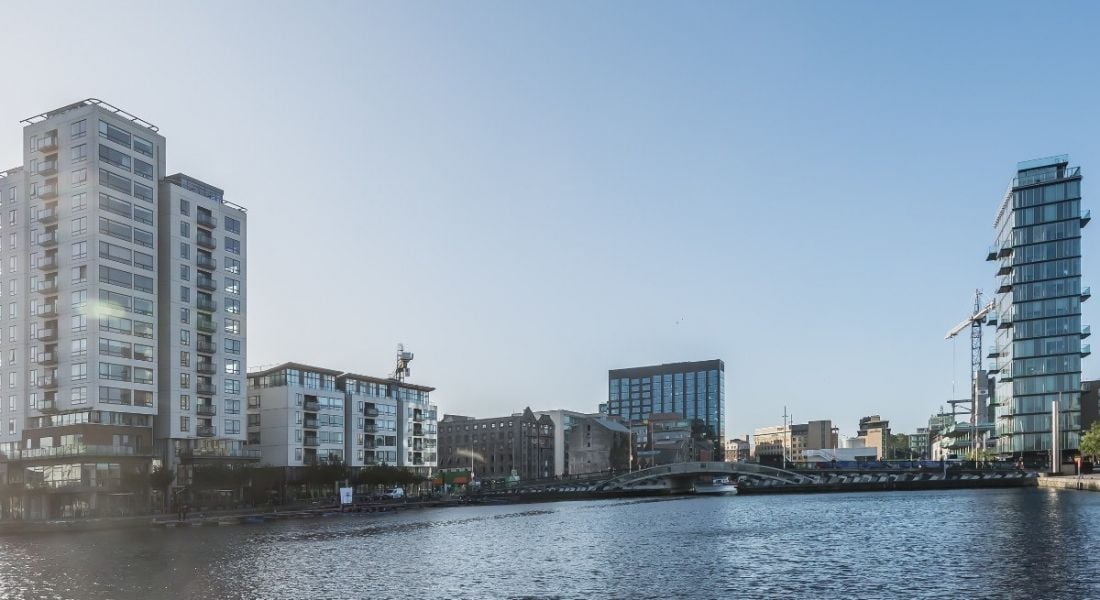 Panorama of Silicon Docks skyline in Dublin with a blue sky reflecting on water.