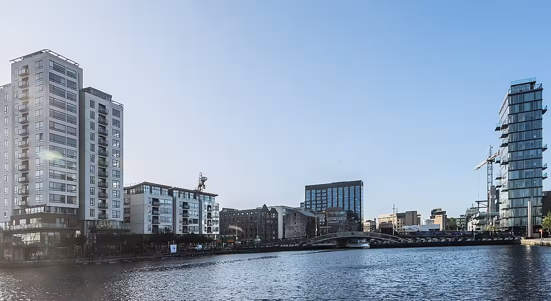 Panorama of Silicon Docks skyline in Dublin with a blue sky reflecting on water.