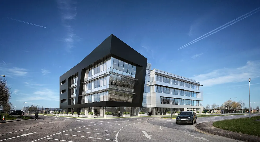 A large, modern, state-of-the art Jaguar Land Rover office exterior with lots of windows and a blue sky in the background.