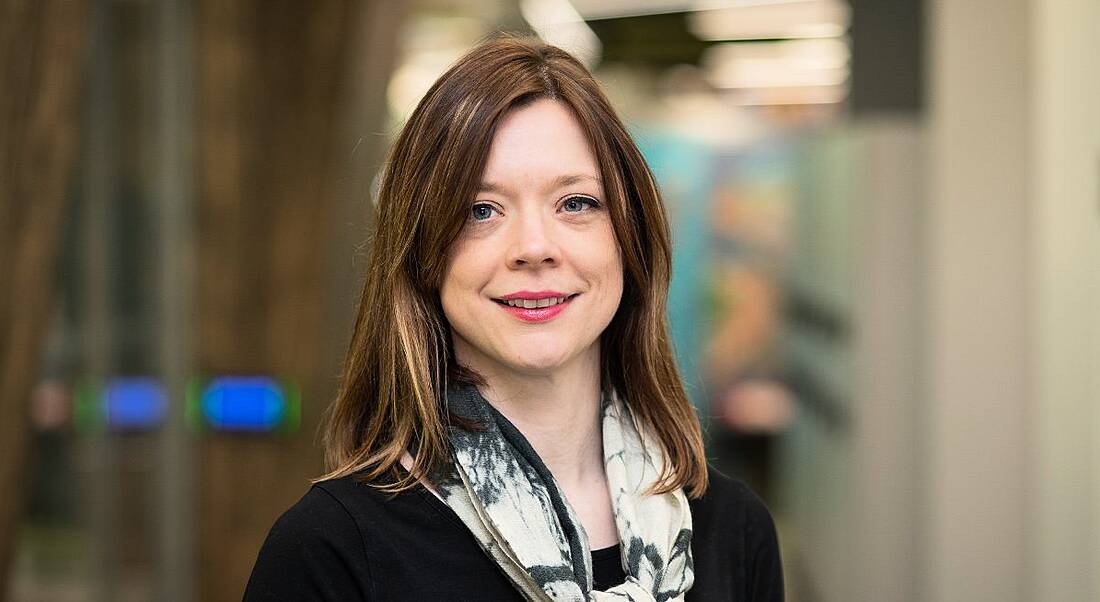 A close-up of a dark-haired young woman in a black blazer smiling. She is the director of design at Fidelity Investments.