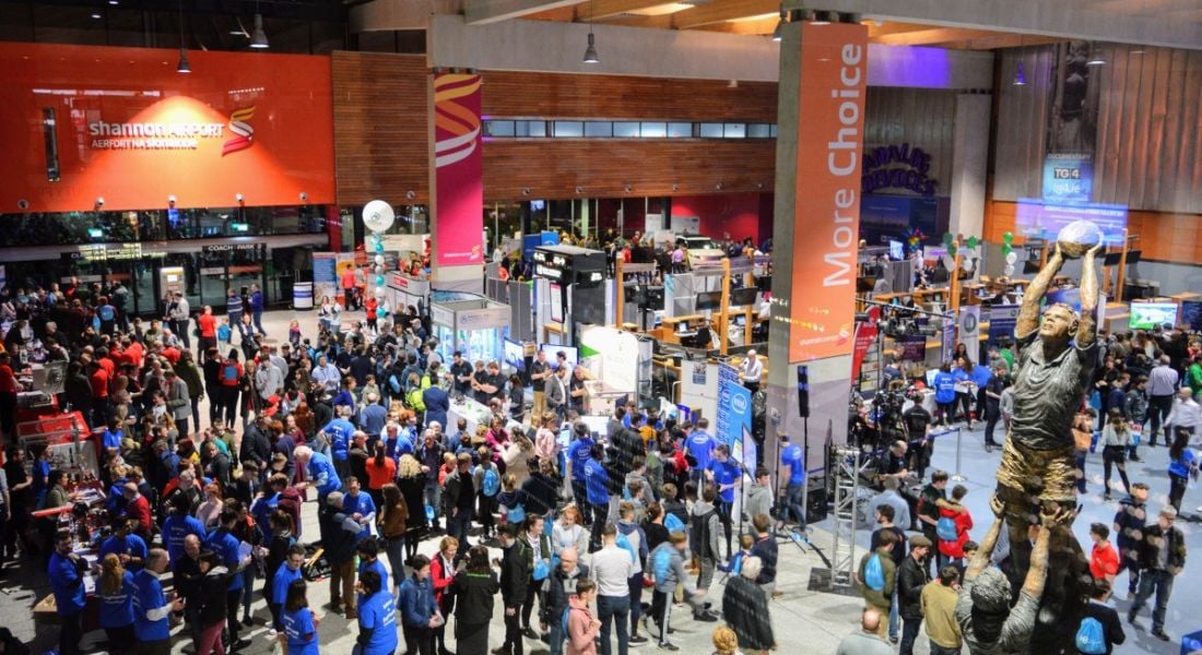 Overhead shot of a large crowd of people gathered in Shannon Airport departures hall among exhibition stands and displays.