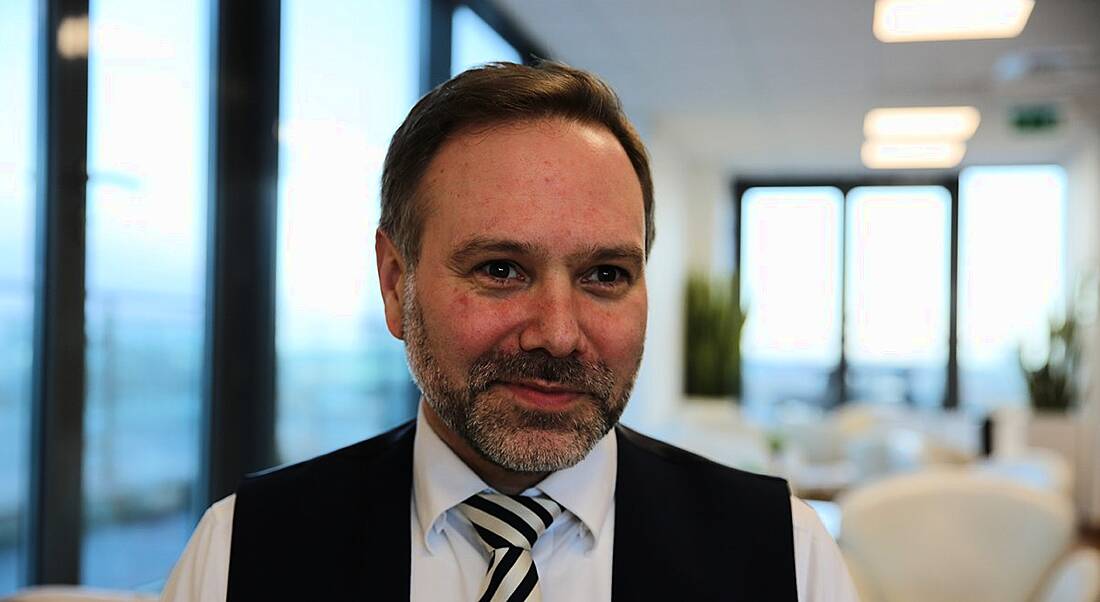 A close-up of a man in a white shirt and black vest with a tie. He is director in SAP at the consulting practice at Deloitte.