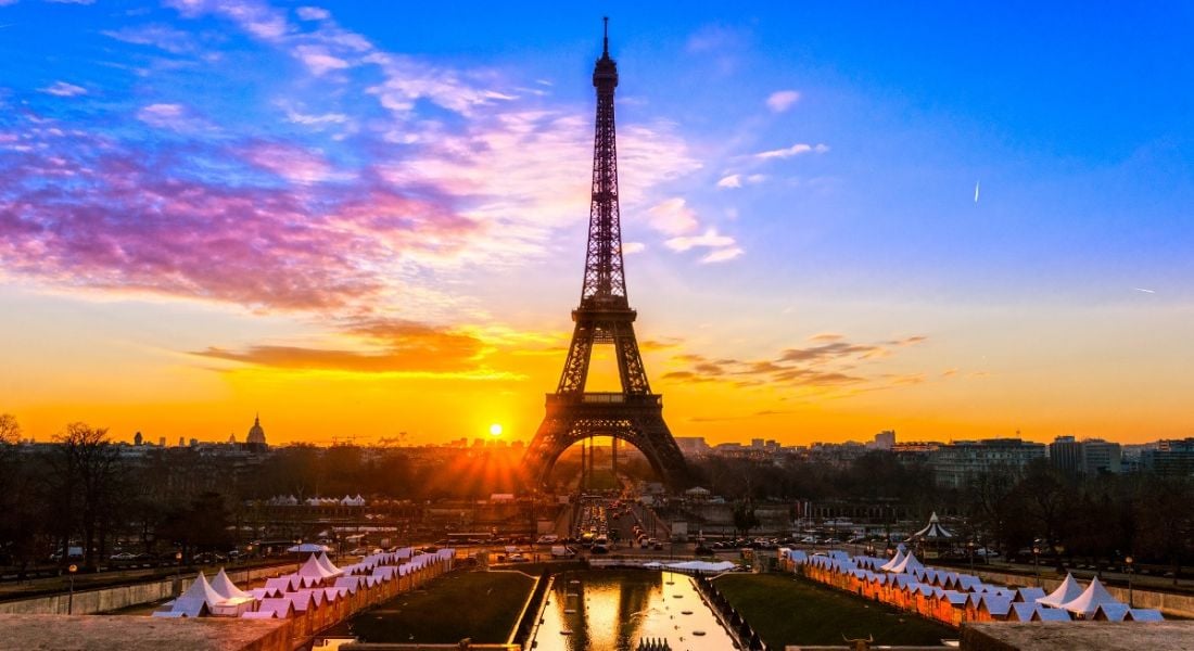 A vibrant sunset in Paris. The Eiffel Tower is in the centre and the sky is deep blue, descending into bright orange.