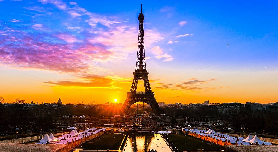 A vibrant sunset in Paris. The Eiffel Tower is in the centre and the sky is deep blue, descending into bright orange.