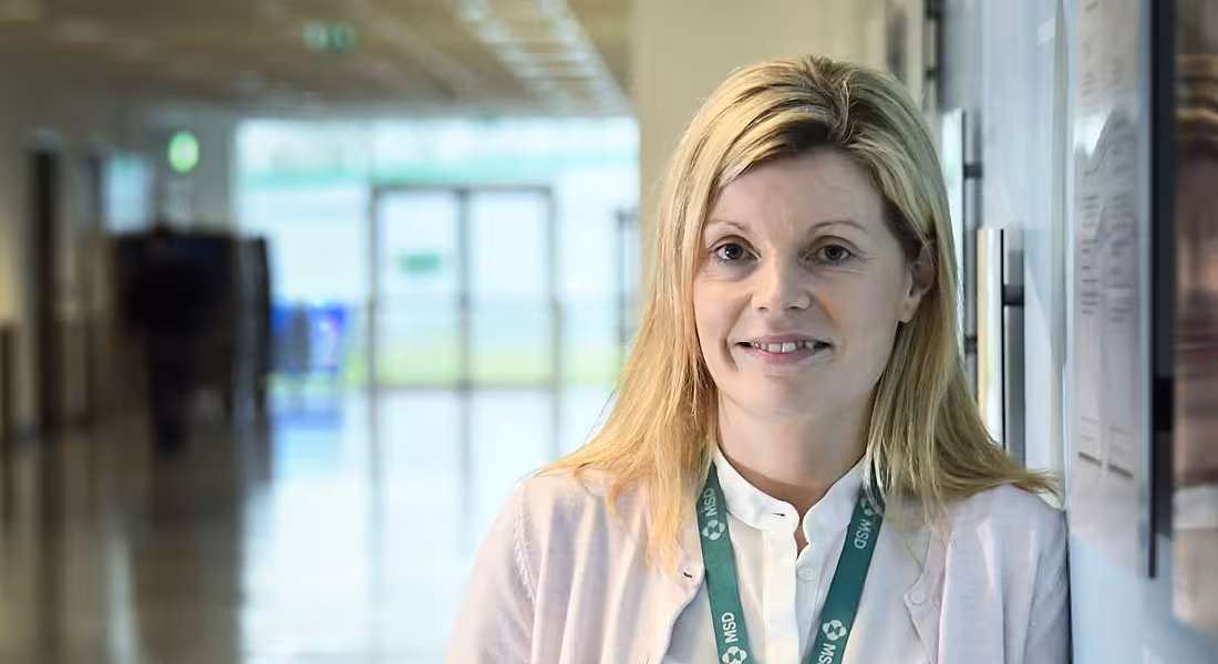 A blonde woman wearing an MSD lanyard looking at the camera in a well-lit hallway.