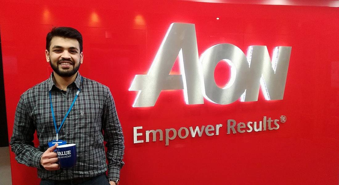 Image of a young man smiling while holding a coffee cup in front of an Aon logo.