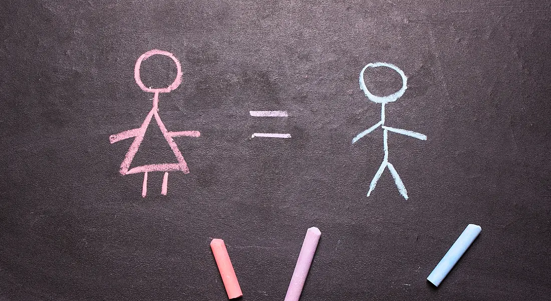 A chalkboard with a pink chalk stick woman with an equals sign beside a blue chalk stick man, showing gender balance.