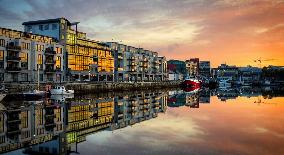 View of buildings with glass facades in Galway dock at sunrise.