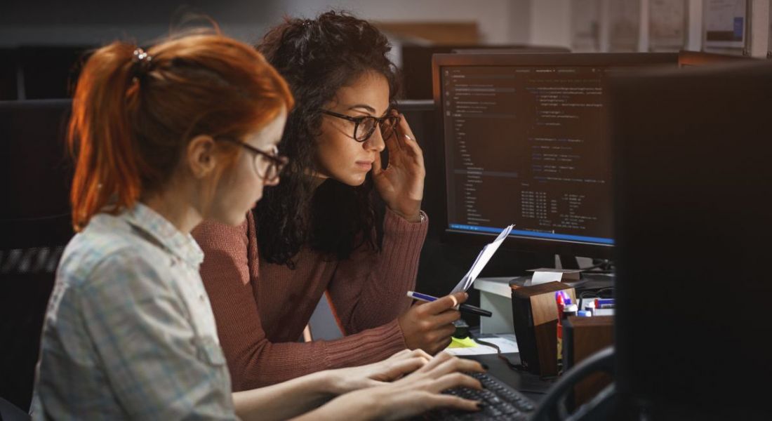 Two women sitting at a computer working.