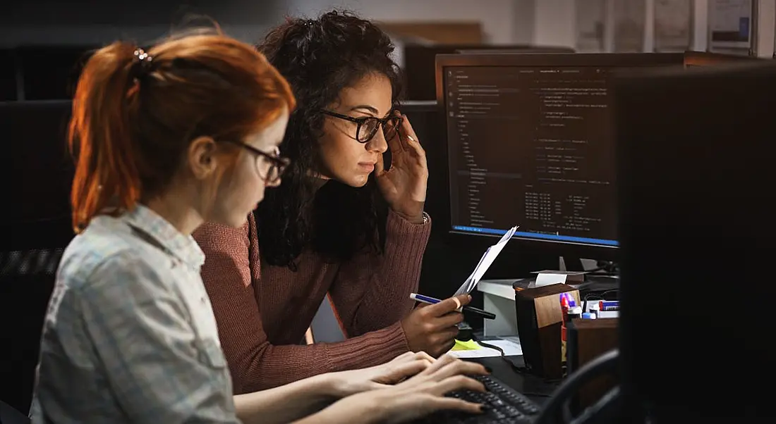 Two women sitting at a computer working.