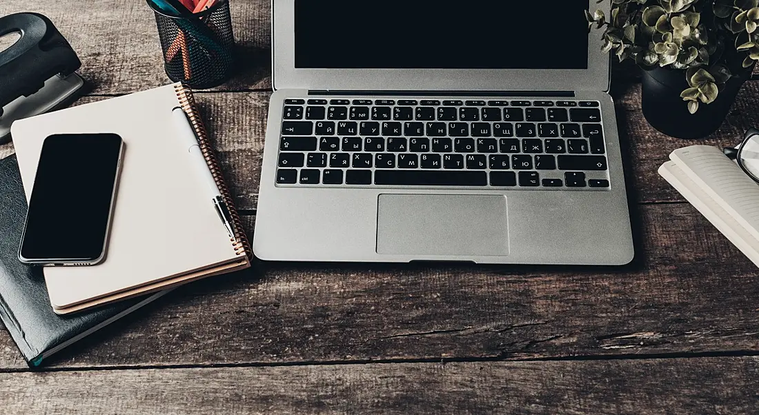 Notebook and laptop on old wooden desk.