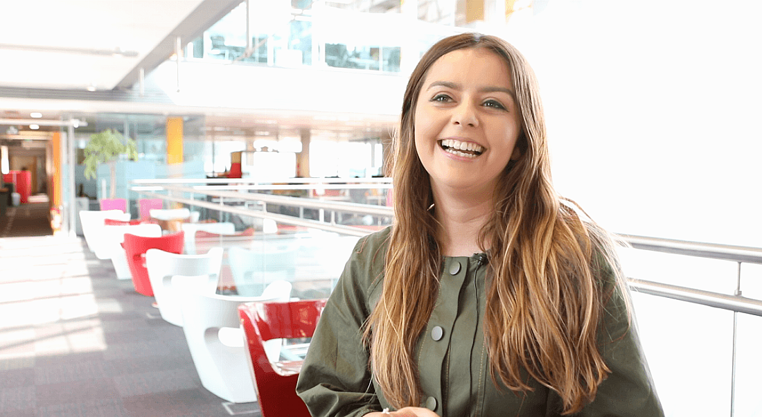 A woman is smiling at something off camera, in a corporate communal setting at PwC.