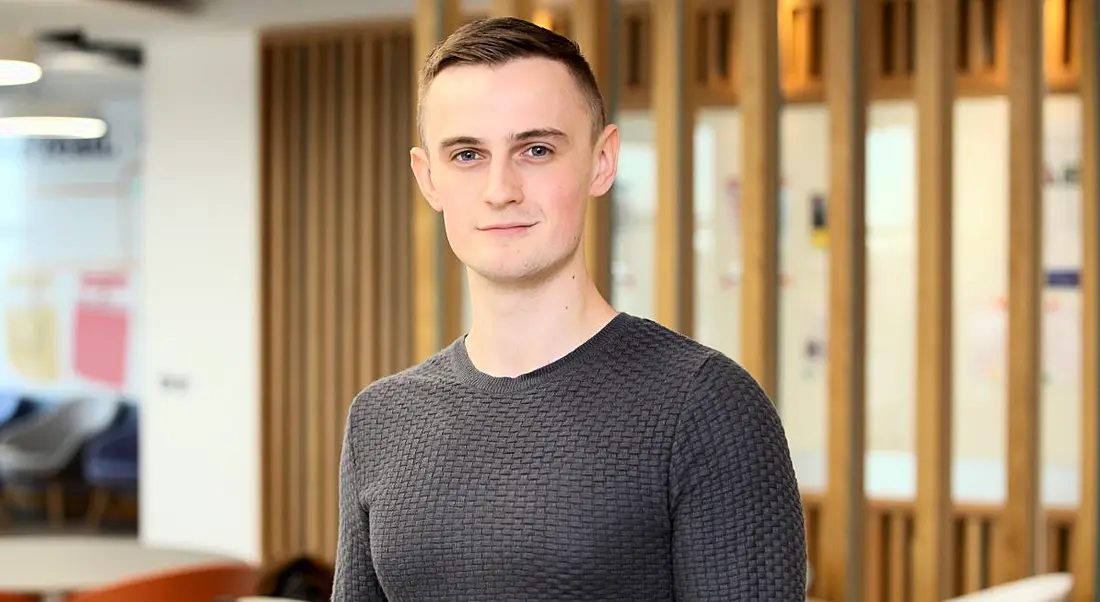 Headshot of a young man in smart casual clothes looking into the camera in a modern corporate setting at Liberty IT, Belfast.