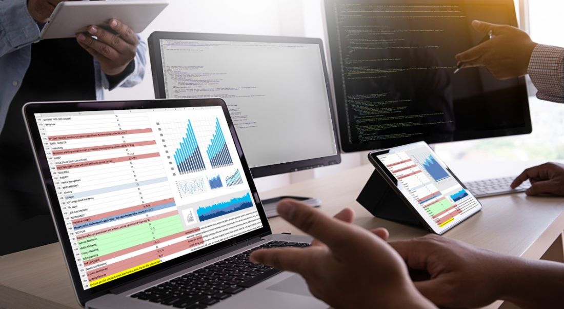 Hands pointing to analytics and statistics on computer screens.