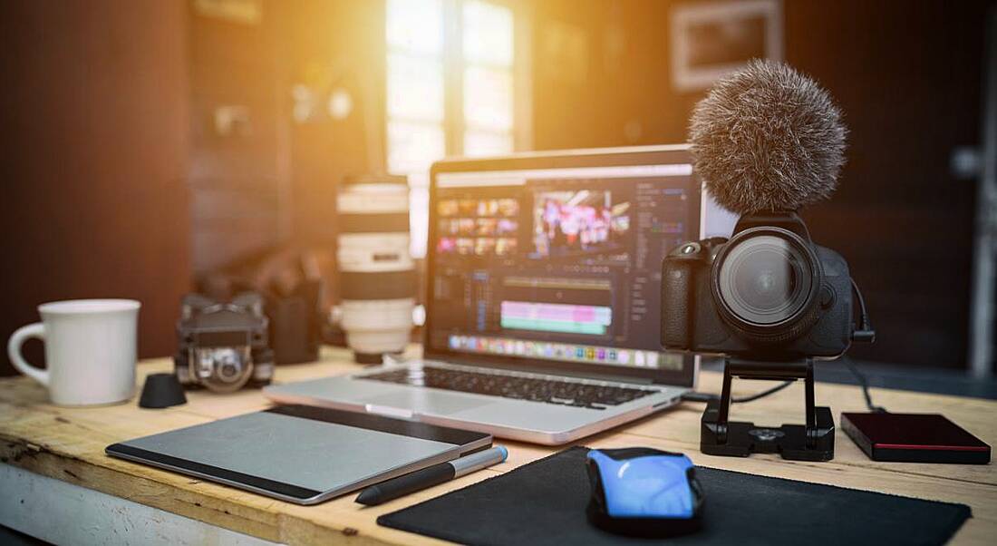 Work desk with a laptop, camera and other technology.