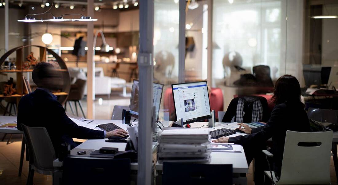 Blurred photo of a modern office space with people working at computers.