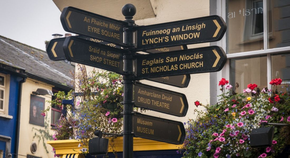 A street signpost in Galway city with arrows pointing to different historical attractions.