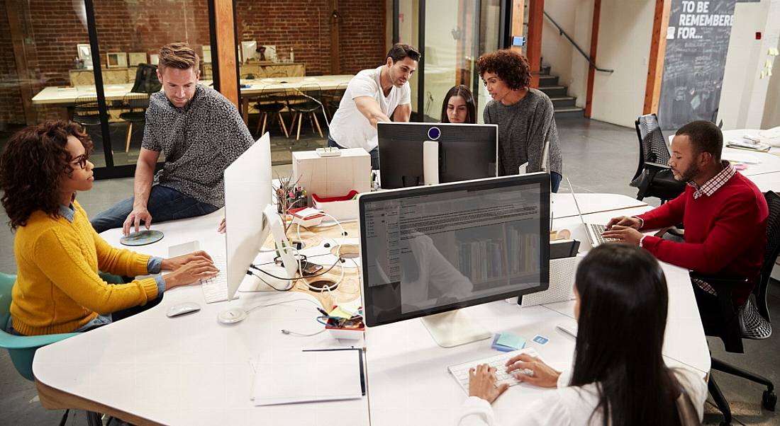 Casually dressed business team working at desks in a modern open-plan office.