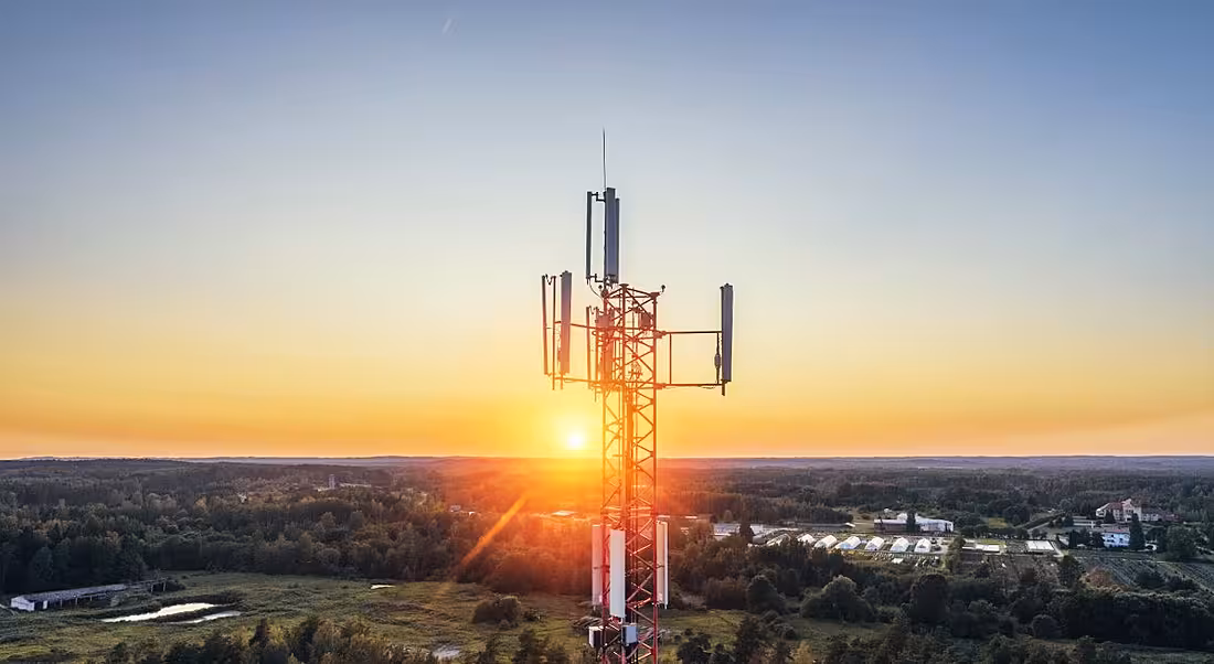 View of telecoms tower against cloudless sky at sunrise.