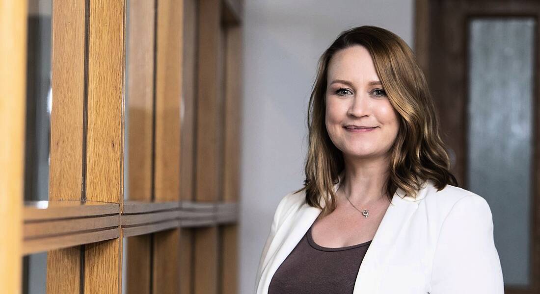 A professional woman in business attire is smiling into the camera in an office setting at MSD, Dublin.