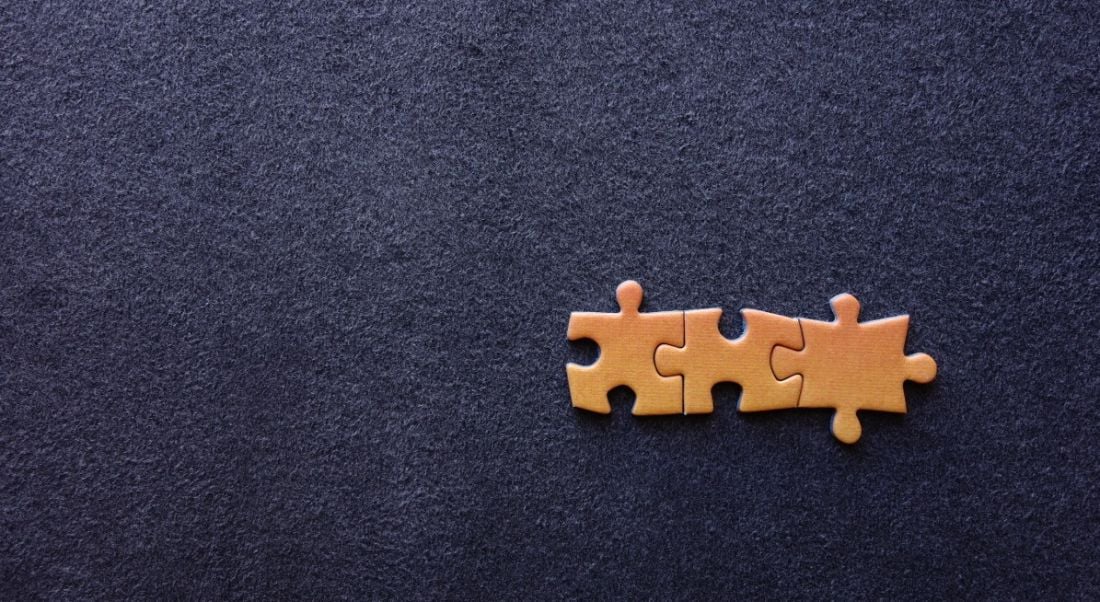 Three orange puzzle pieces stuck together, sitting on a dark blue background.