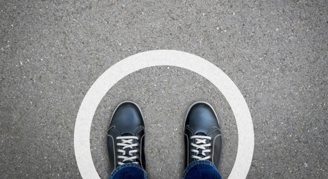 Black shoes standing in white circle on asphalt concrete floor.