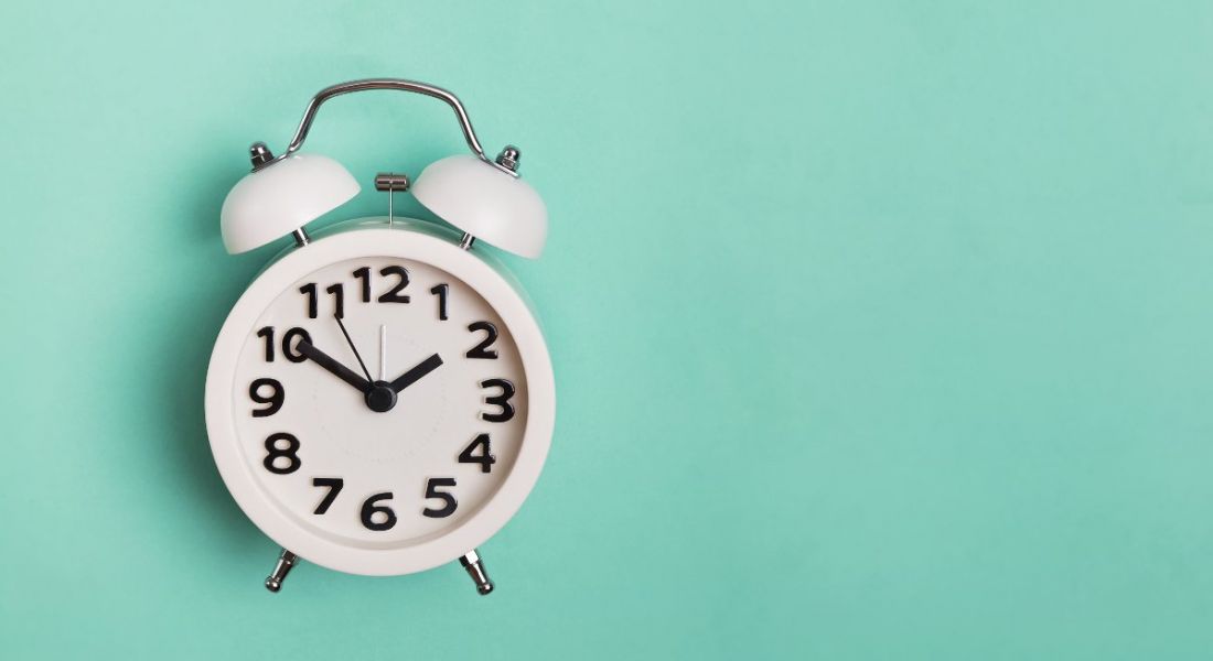 Vintage alarm clock isolated on pastel mint background.
