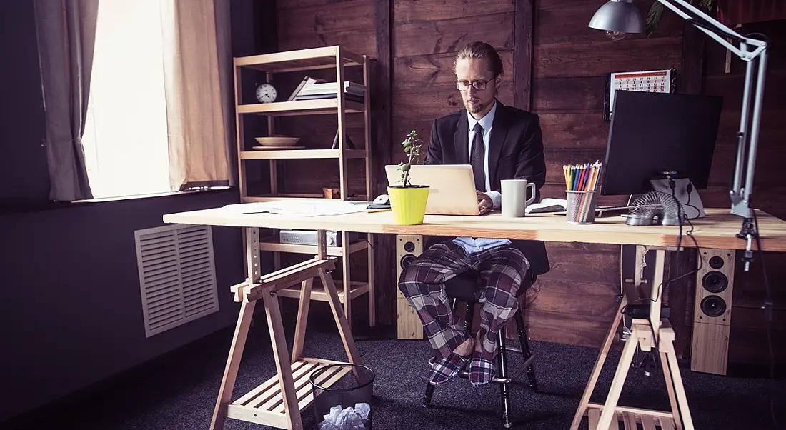 Employee remote working from home wearing a suit jacket and pyjama bottoms and slippers.