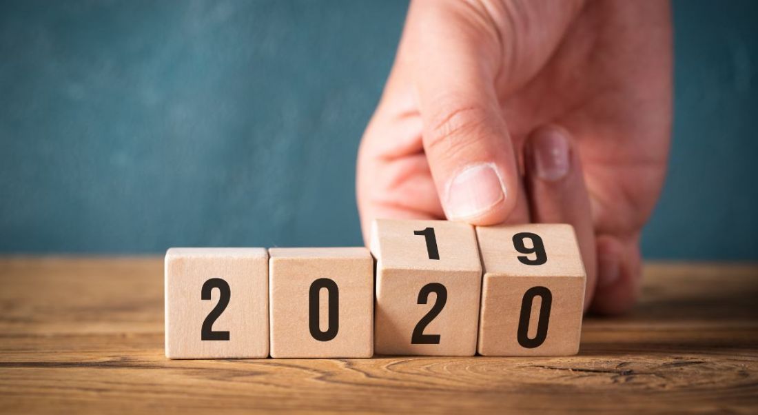 Hand flipping wooden cubes from year 2019 to 2020.