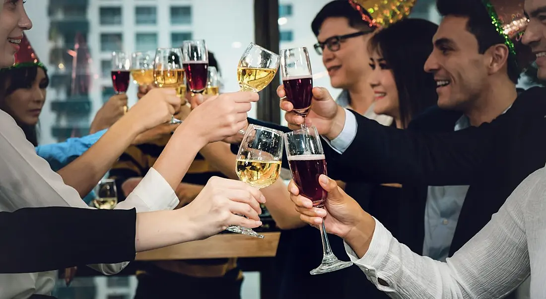 Group of business people enjoying party and clinking glass of champagne and wine together at Christmas party.