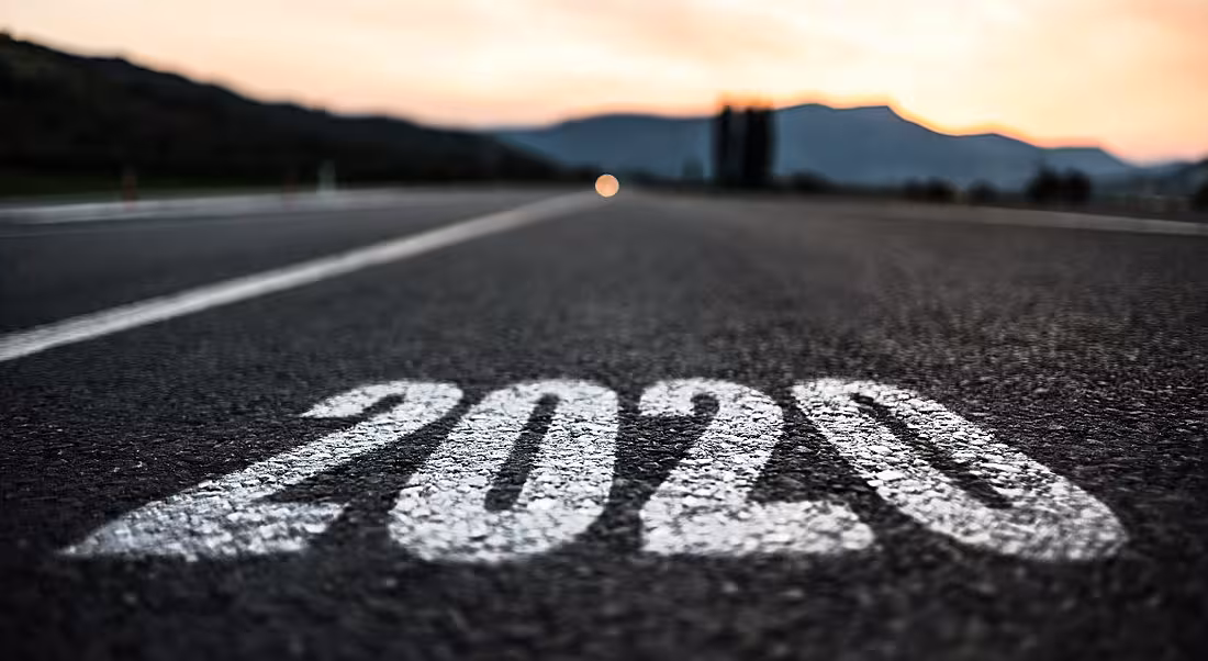 Empty asphalt road stretching into the distance with 2020 painted in white on the ground.