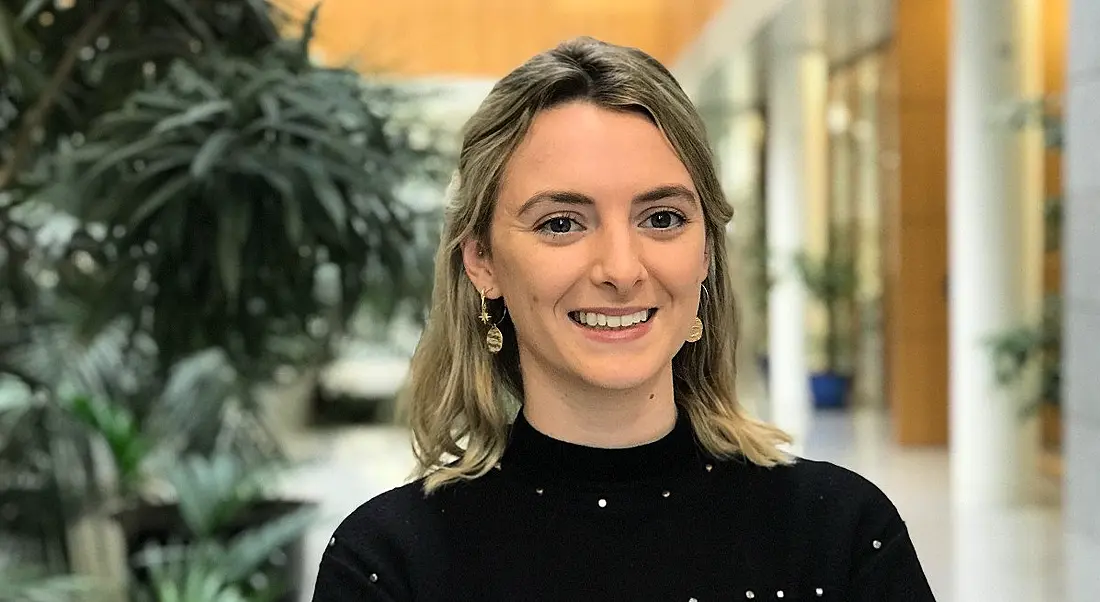 A professional woman is smiling into the camera in Citi offices in Dublin, with indoor plants behind her.