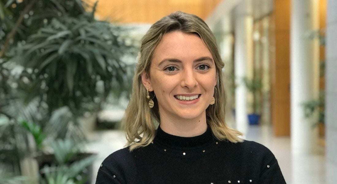 A professional woman is smiling into the camera in Citi offices in Dublin, with indoor plants behind her.