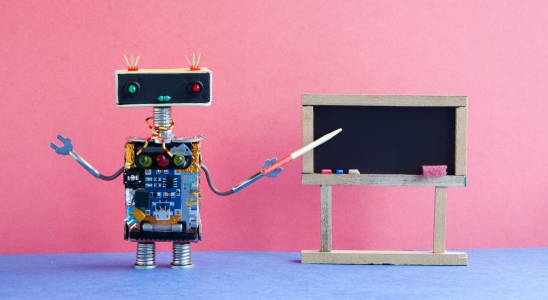 A toy robot is teaching using a blackboard in a colourful classroom setting.