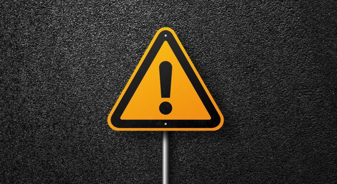 A triangular yellow warning sign with an exclamation mark in the middle against a dark background.