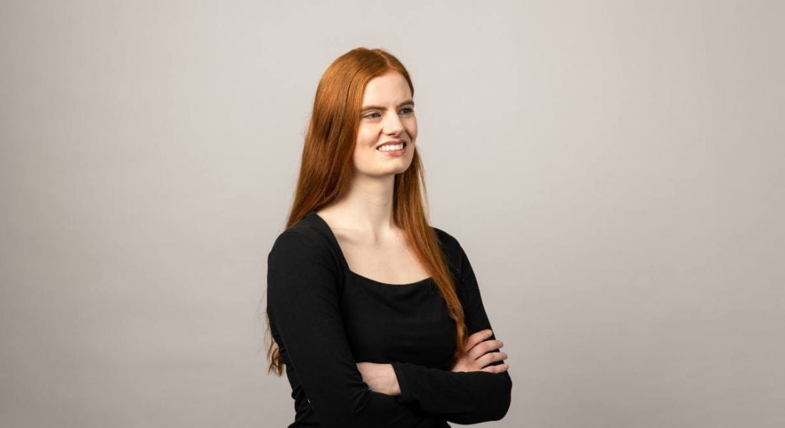 Bioprocess associate at BMS, Emma Bennett-Wren, wearing a black top, looks away from the camera, smiling.
