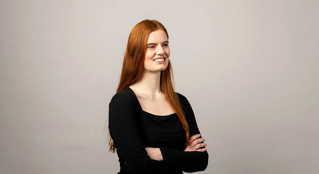 Bioprocess associate at BMS, Emma Bennett-Wren, wearing a black top, looks away from the camera, smiling.