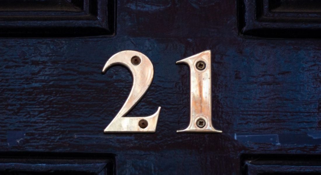 The gold number 21 nailed onto a dark blue door.