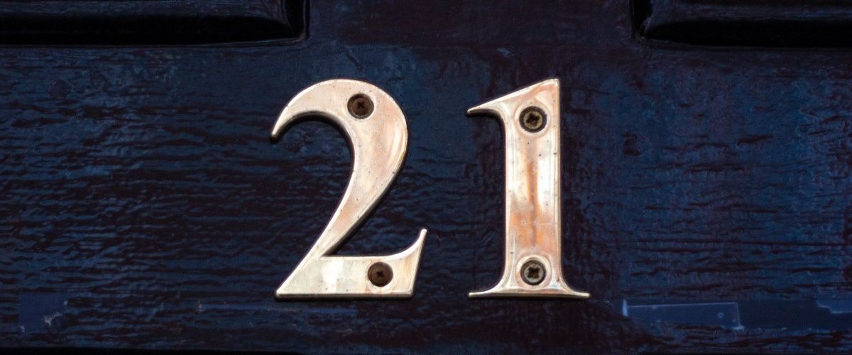 The gold number 21 nailed onto a dark blue door.