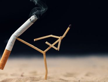 A matchstick constructed to look like it is practising karate kicks a cigarette in the air indicating the banning of smoking.
