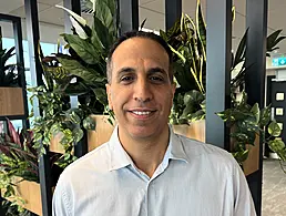 A man smiling while holding up a square cushion that says Workhuman on it.