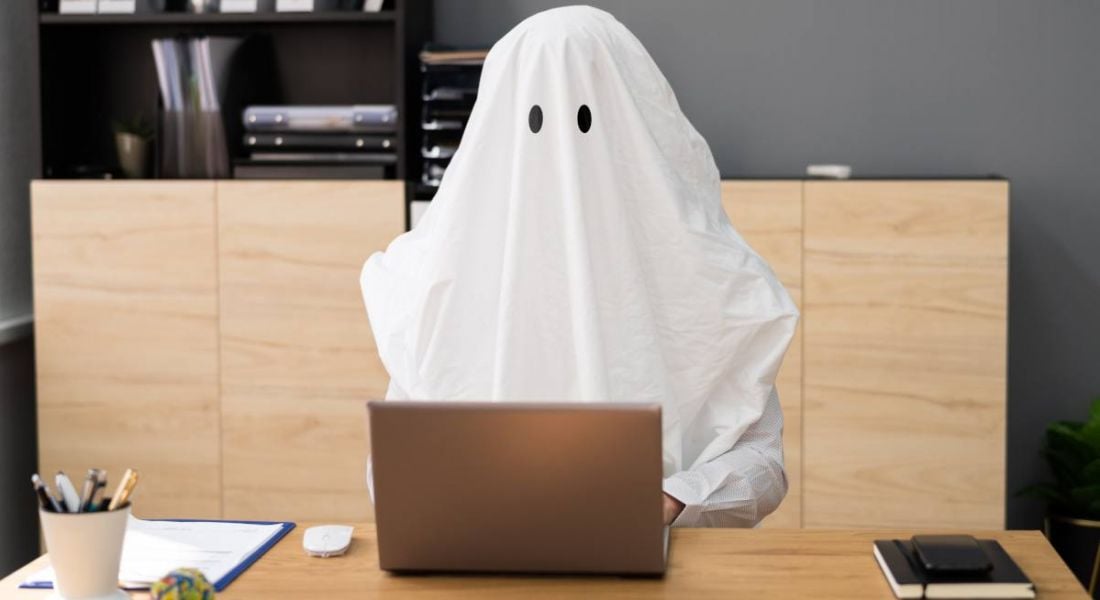 In a representation of ghosting in the workplace a ghost that appears to be a business person sits at a computer, working.