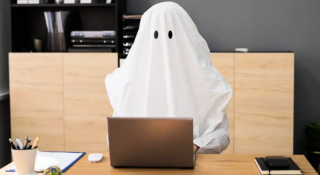 In a representation of ghosting in the workplace a ghost that appears to be a business person sits at a computer, working.