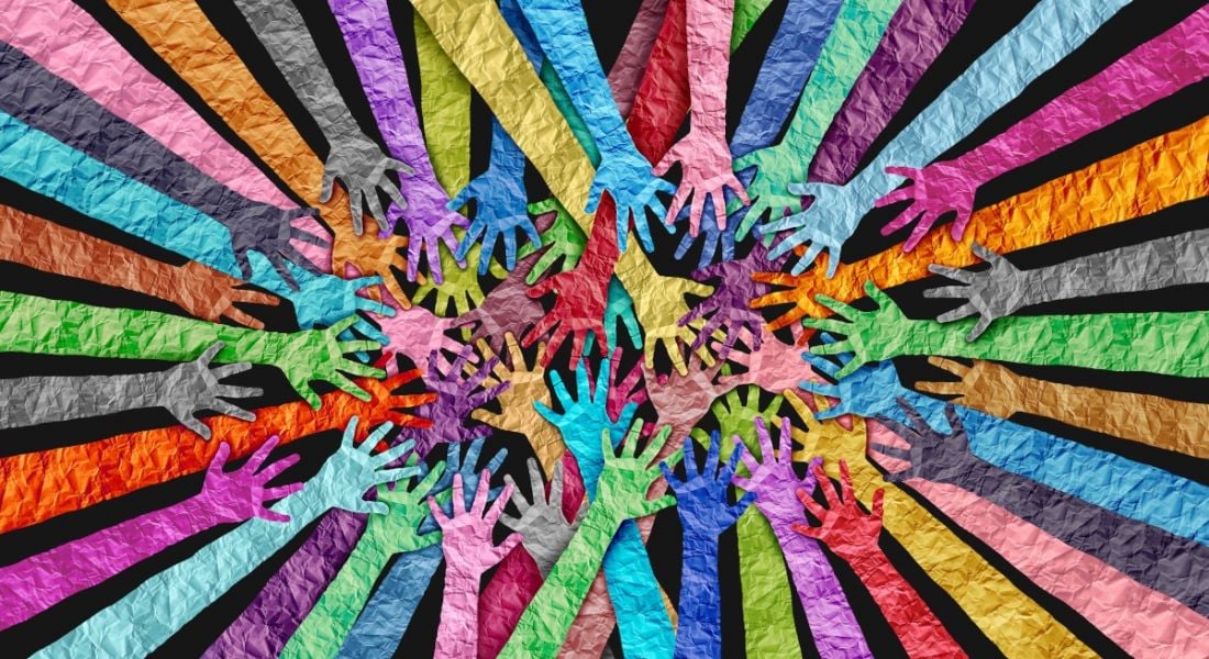 Rainbow coloured hands reach out against a black background, symbolising the importance of diversity and collaboration.