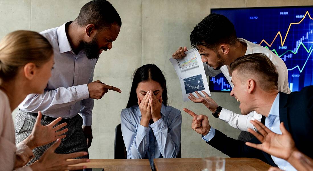 A woman covers her face, overwhelmed by the pressures of her work, in a representation of psychosocial hazards.