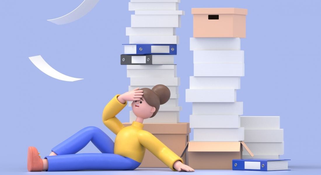 A woman, exasperated by workplace bureaucracy, leans against a stack of paperwork.